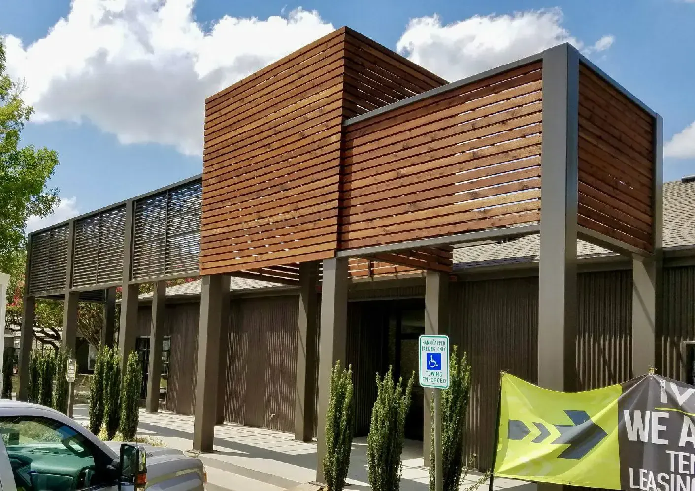 Modern building with wood slats, a handicap parking sign, and leasing sign.