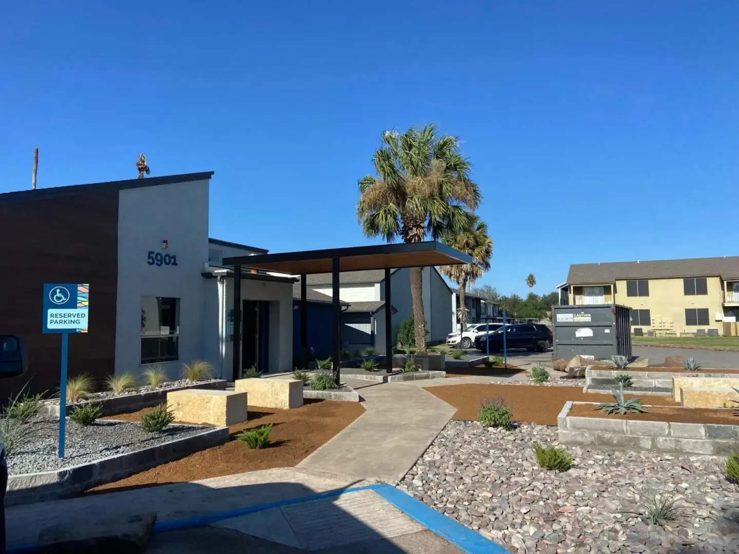 Exterior of apartment complex entrance with accessible parking sign.