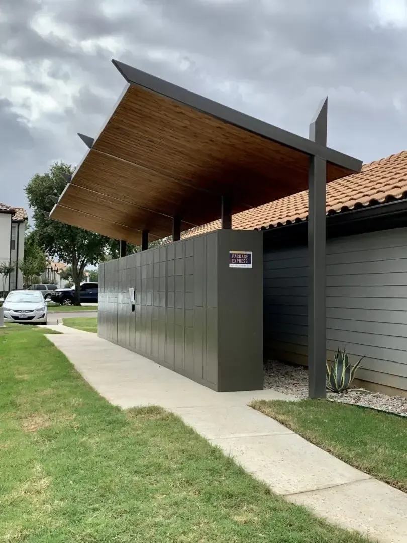 Mail lockers with a wooden-covered roof, pathway, and green lawn.