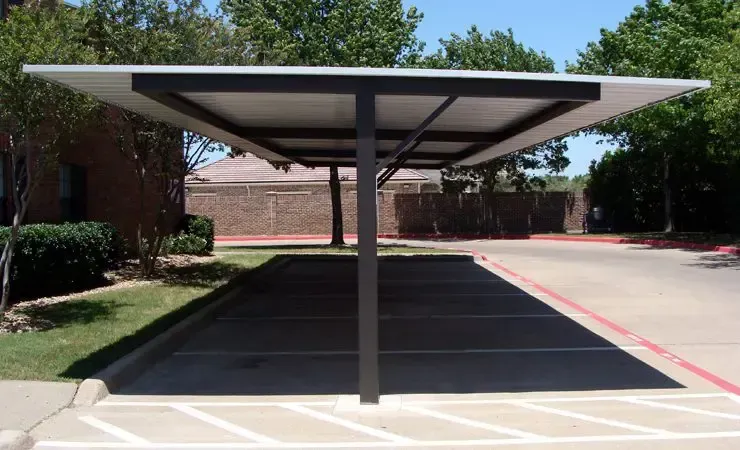 Carport over parking spaces; white roof, dark supports, sunny outdoor setting.