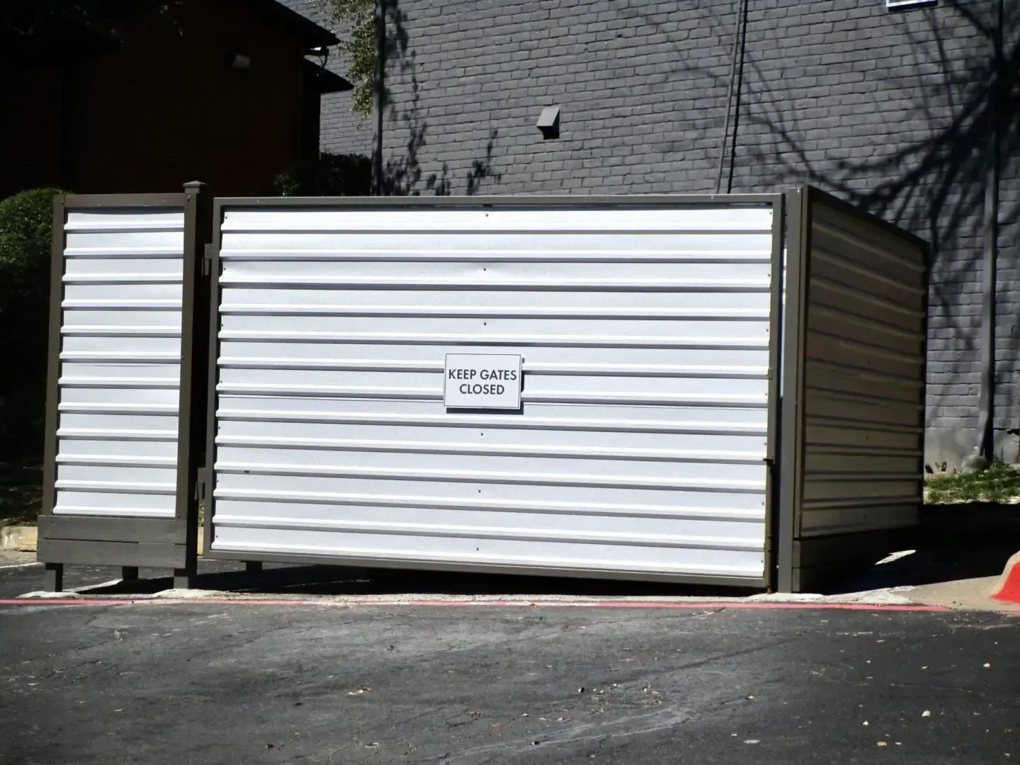 White metal storage container with a small sign, in an outdoor setting.