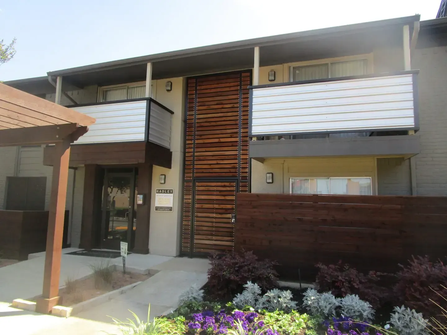 Apartment building exterior with wooden accents, balconies, and landscaping.