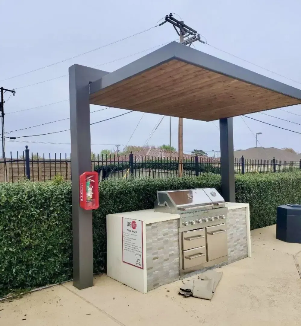 Outdoor grilling station with a fire extinguisher, under a gray canopy.