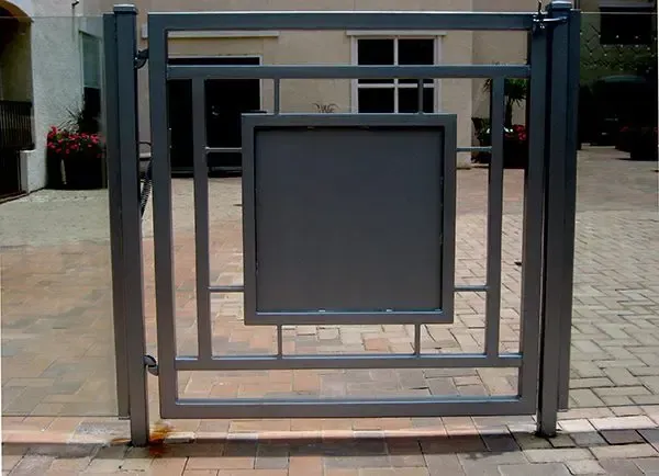 Gray metal gate with a square panel and geometric design in a courtyard.