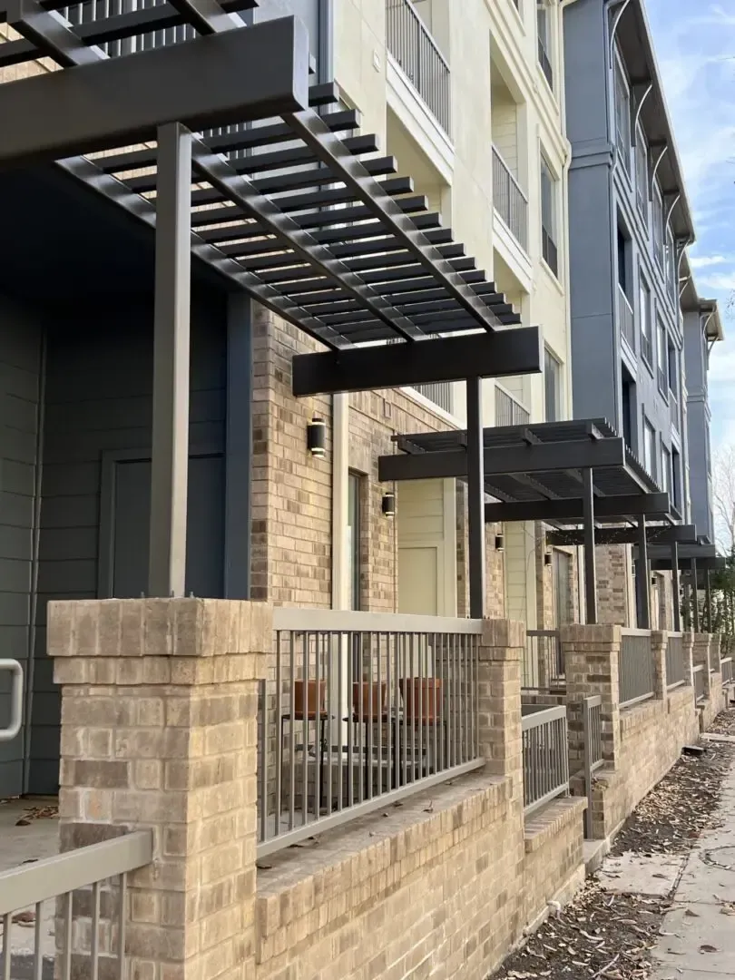 Exterior of apartments with brick and gray metal pergolas.