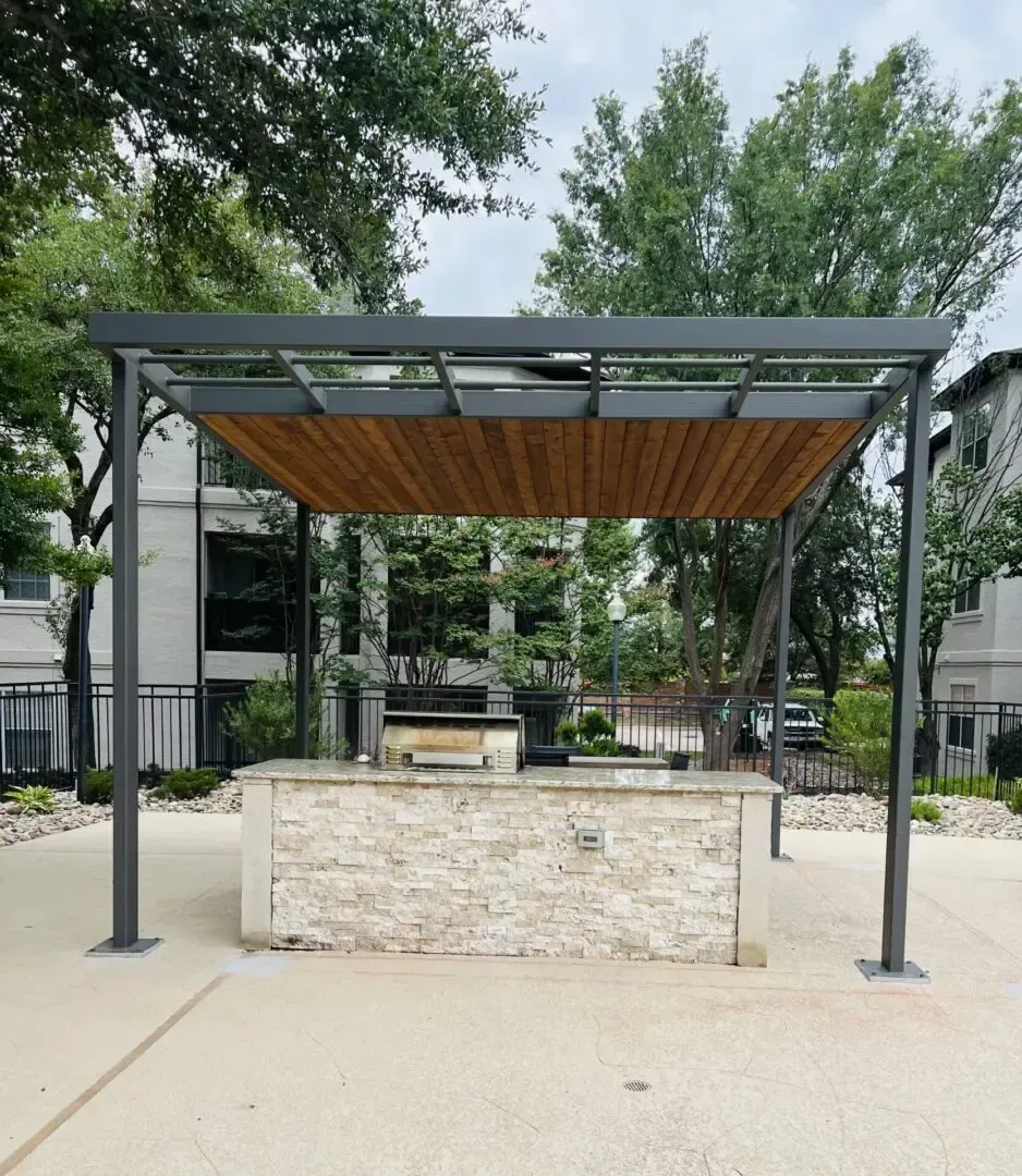Outdoor grill area with a gray pergola and a stone counter.