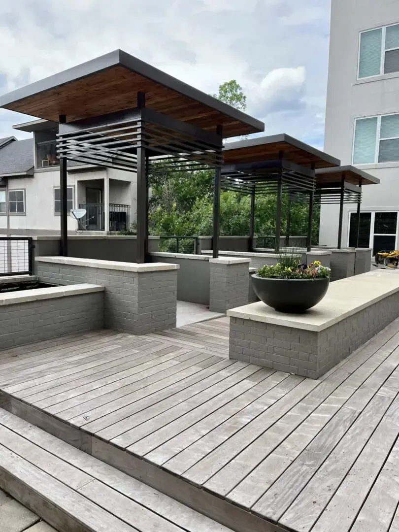 Outdoor patio with three shaded seating areas; grey wood, stone, and metal.