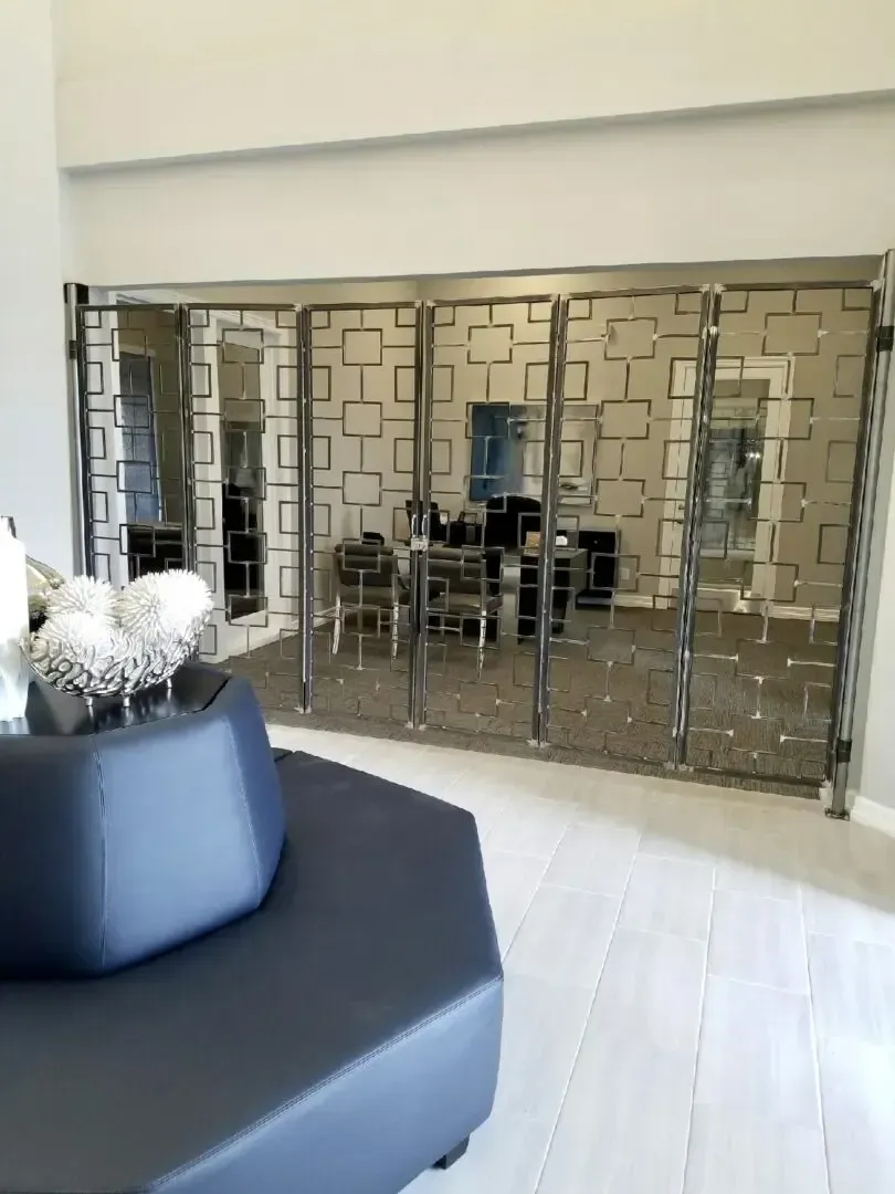 Reception area with a patterned metal screen, a dark blue hexagonal seat, and chairs.