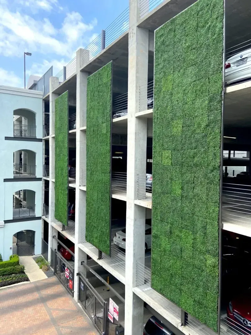 Exterior of a parking garage with green vertical panels; multi-level structure with parked cars.