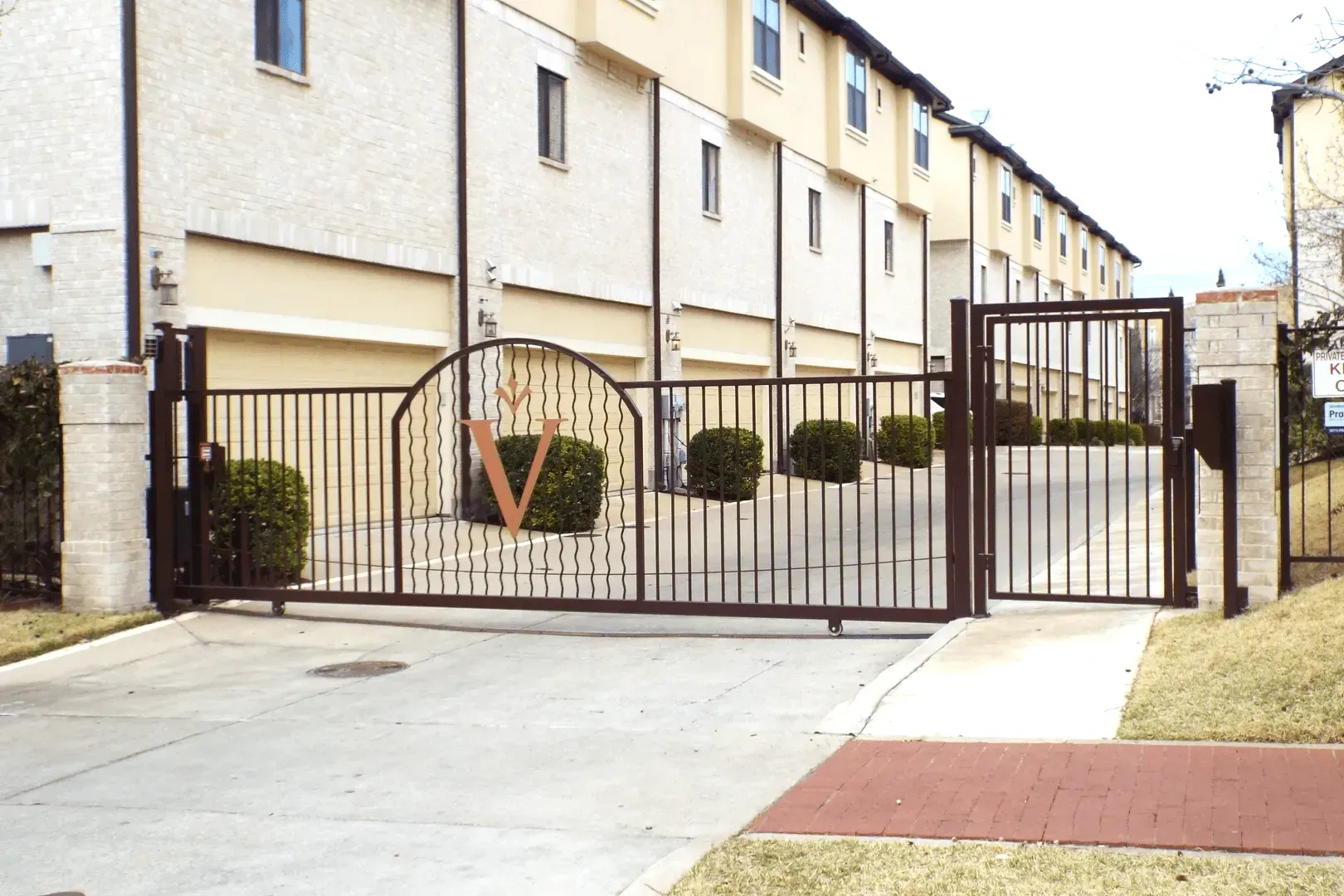Gated entrance to a townhome community. Brown metal gate with an