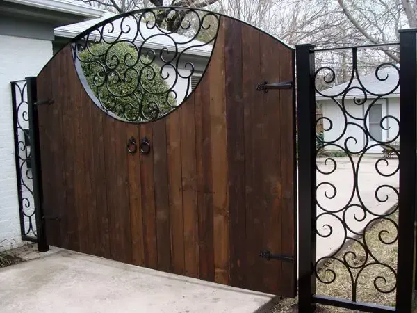 Wooden gate with decorative ironwork, in a residential setting.