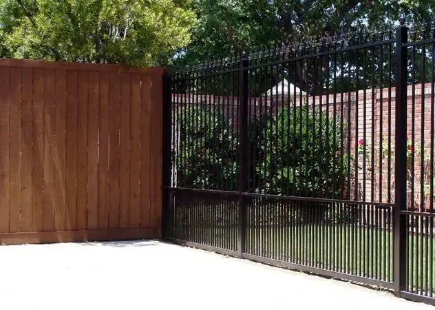 A wooden fence transitions to a black metal fence, enclosing a yard.