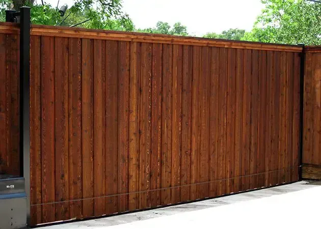Wooden sliding gate, stained brown, in front of a concrete surface.