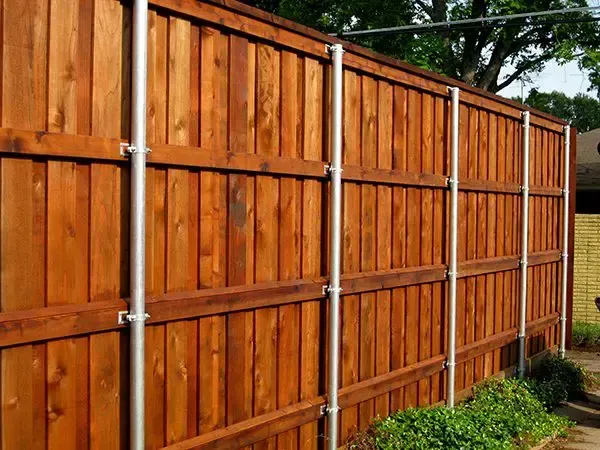 Wooden privacy fence with silver metal posts, stained dark brown.