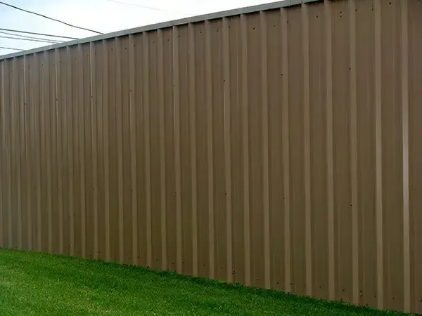 Brown corrugated metal wall beside green grass.