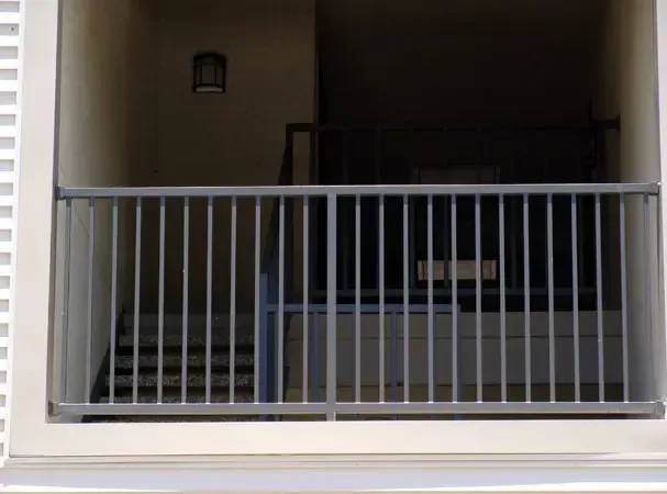 Gray metal railing in front of stairs, viewed from outside the building.