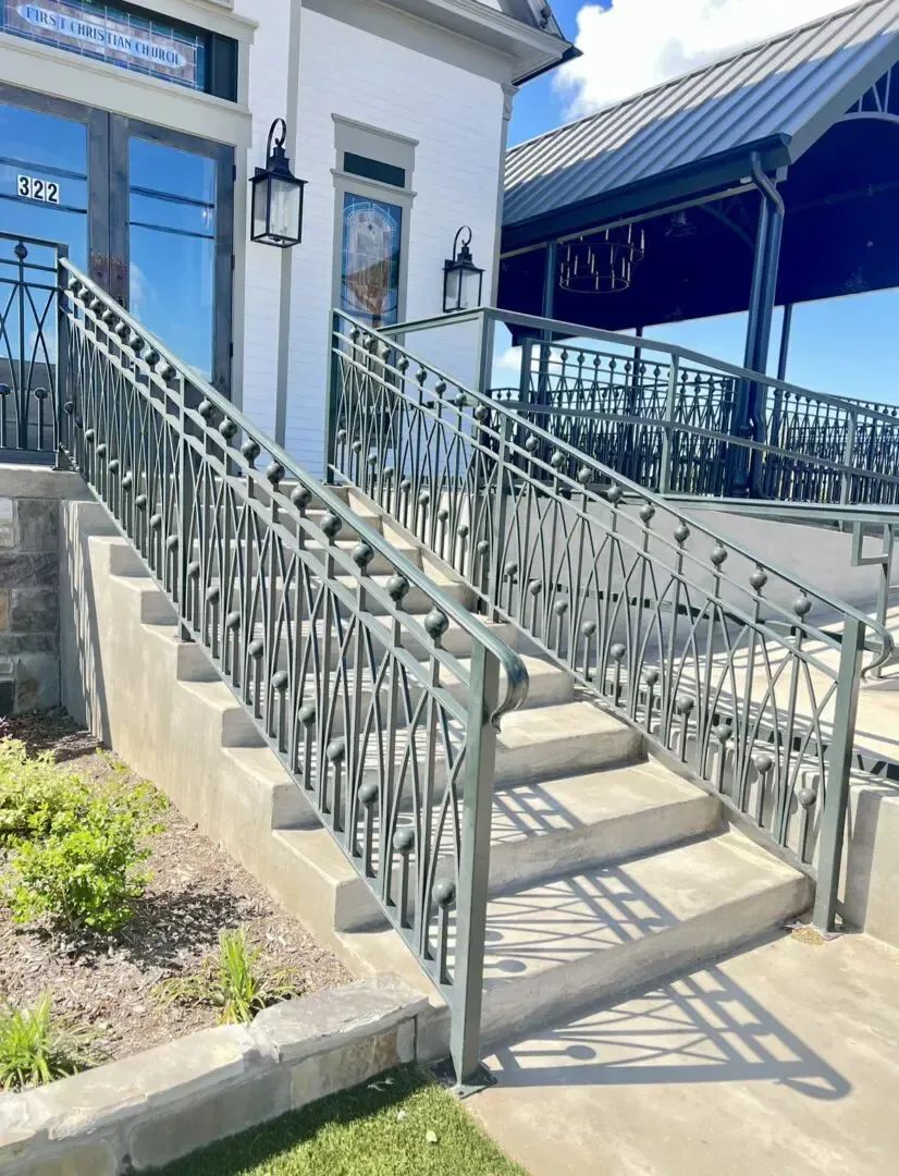 Concrete stairs with decorative metal railing leading to a building entrance.