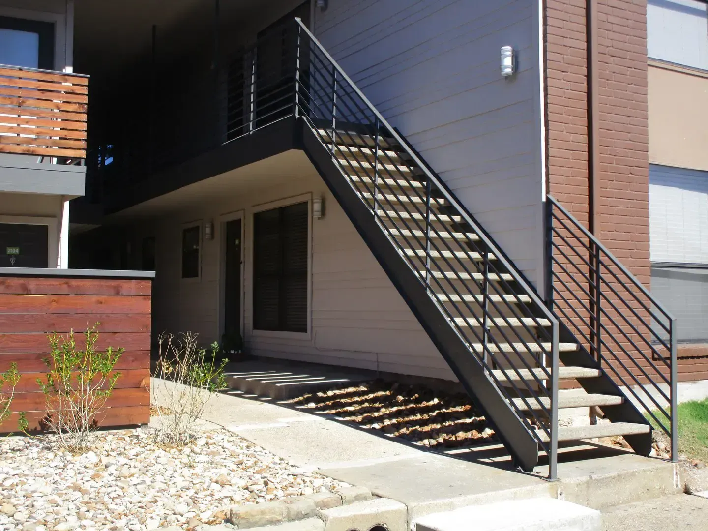 Exterior staircase leading to a building entrance with metal railings and a light-colored exterior wall.