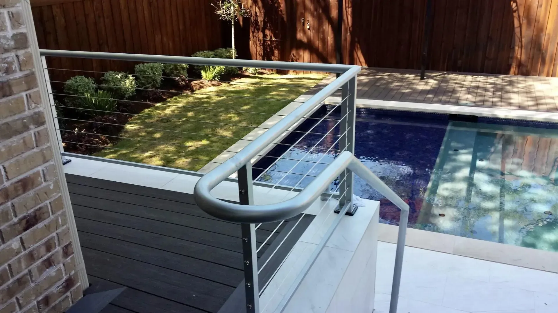 Exterior view of steps leading to a pool with stainless steel handrails.