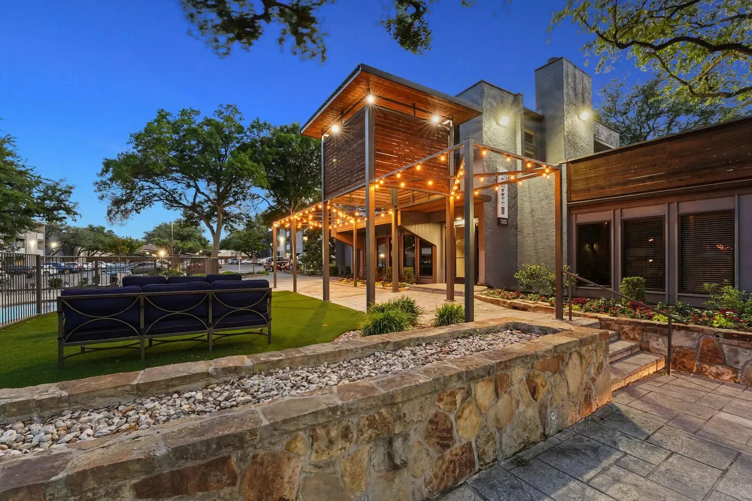 Outdoor restaurant patio at dusk with string lights, stone accents, and a waterfront view.