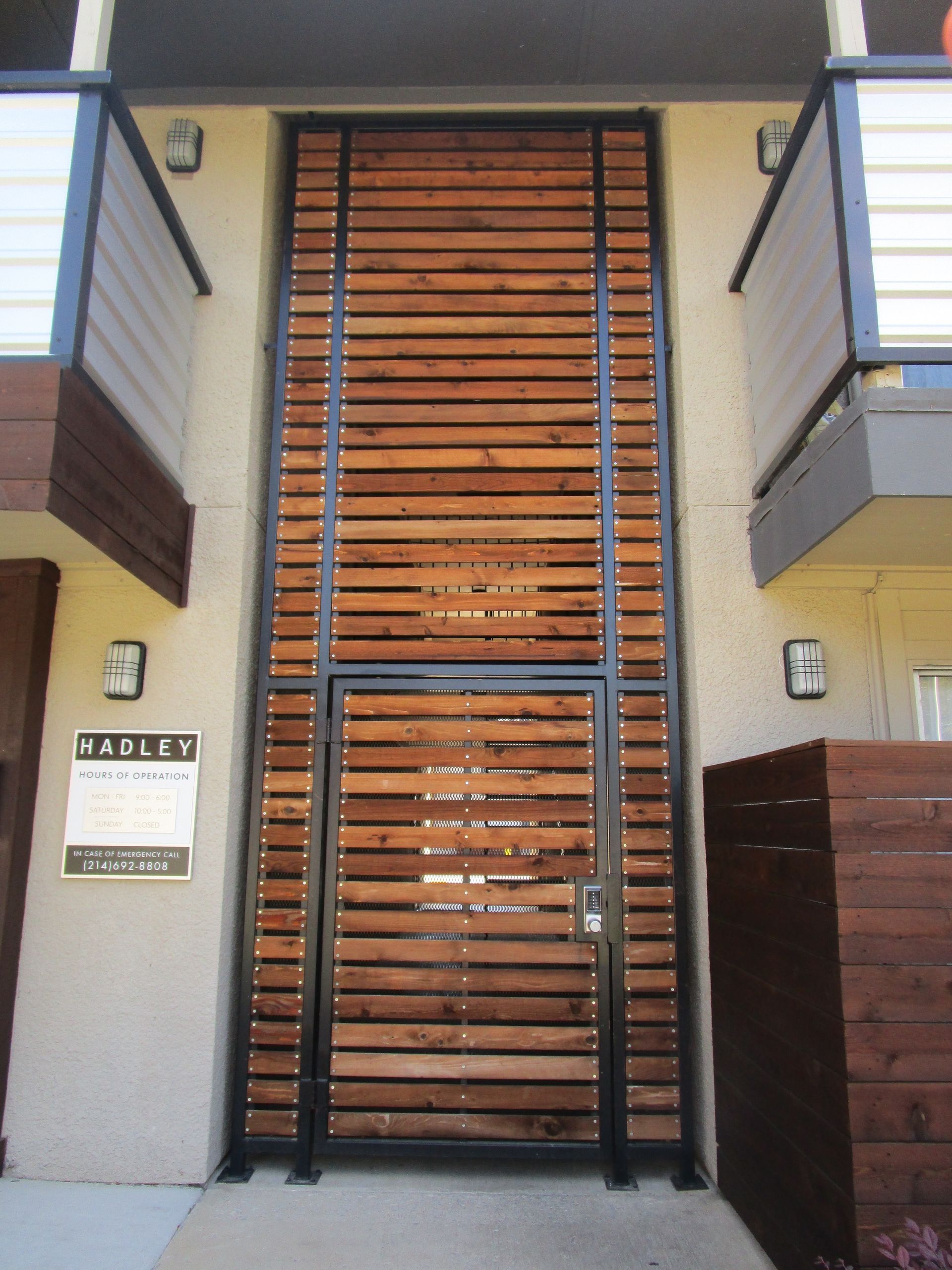 Wooden slat gate with a black metal frame at an apartment entrance.