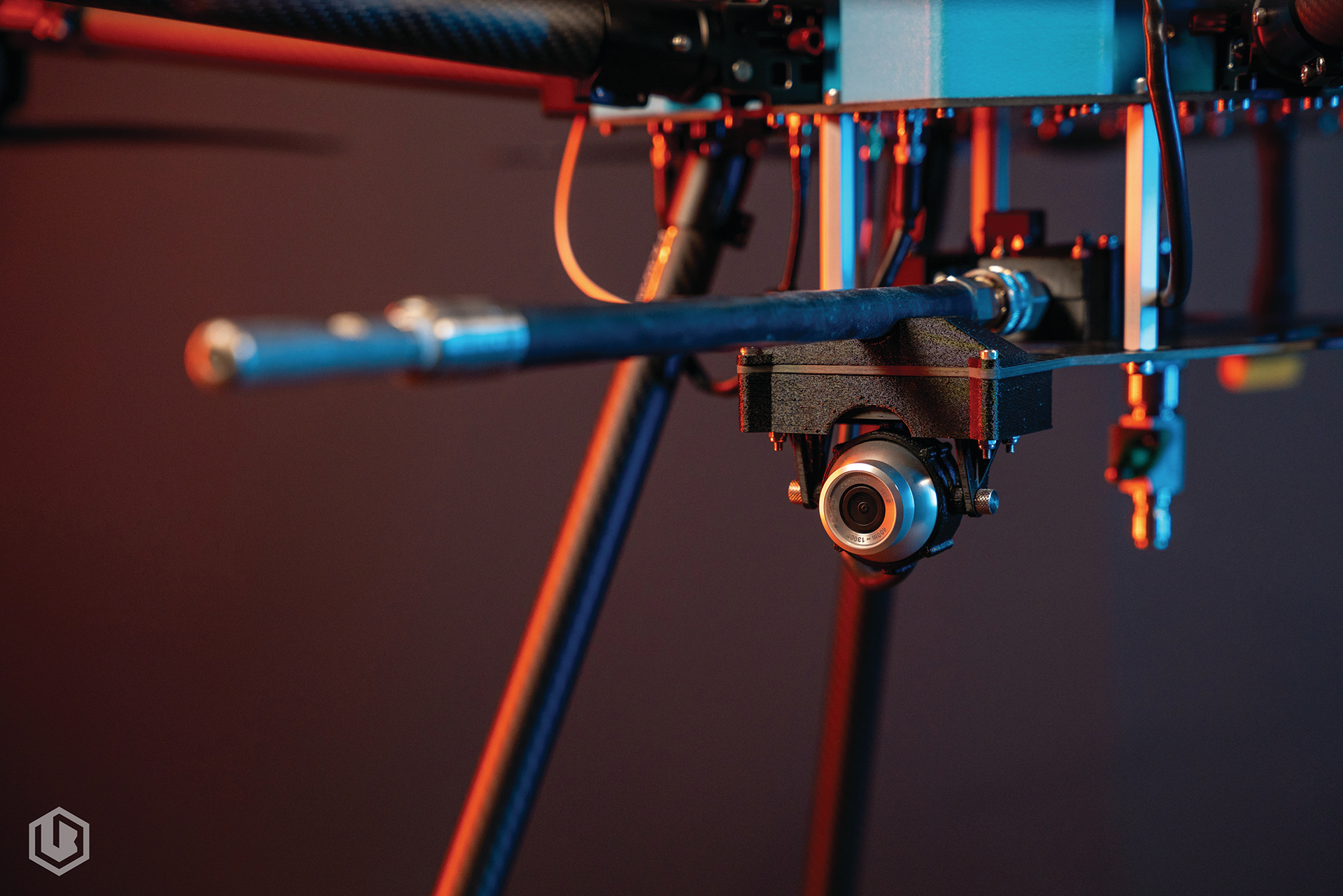 Close-up of a small drone or camera rig with blue arms and lights against a dark background