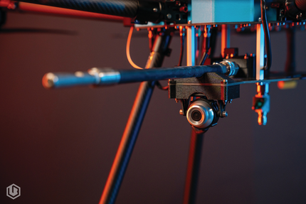 Close-up of a small drone or camera rig with blue arms and lights against a dark background