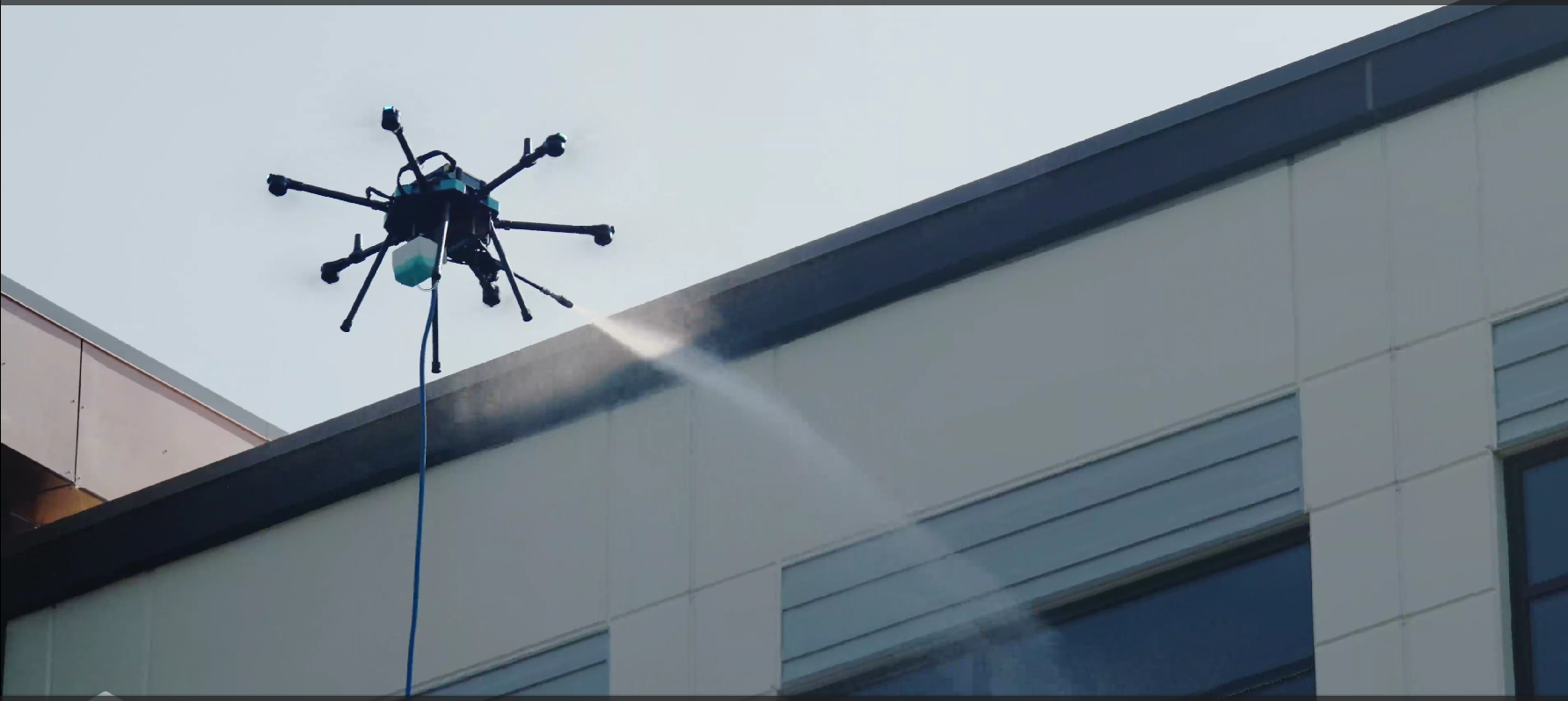 Drone hovering above a building roofline against the sky