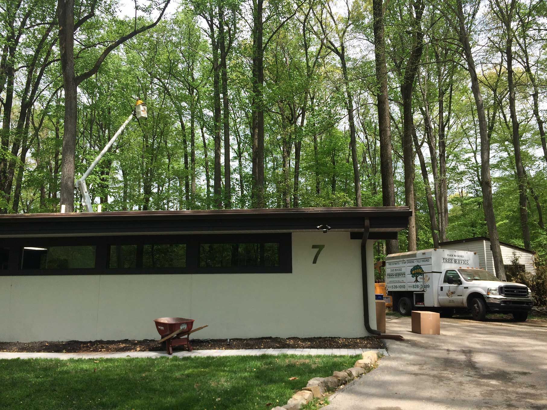 A white house with the number 7 on it is surrounded by trees.
