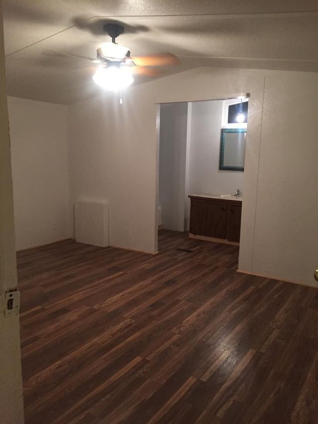 An empty room with hardwood floors and a ceiling fan.