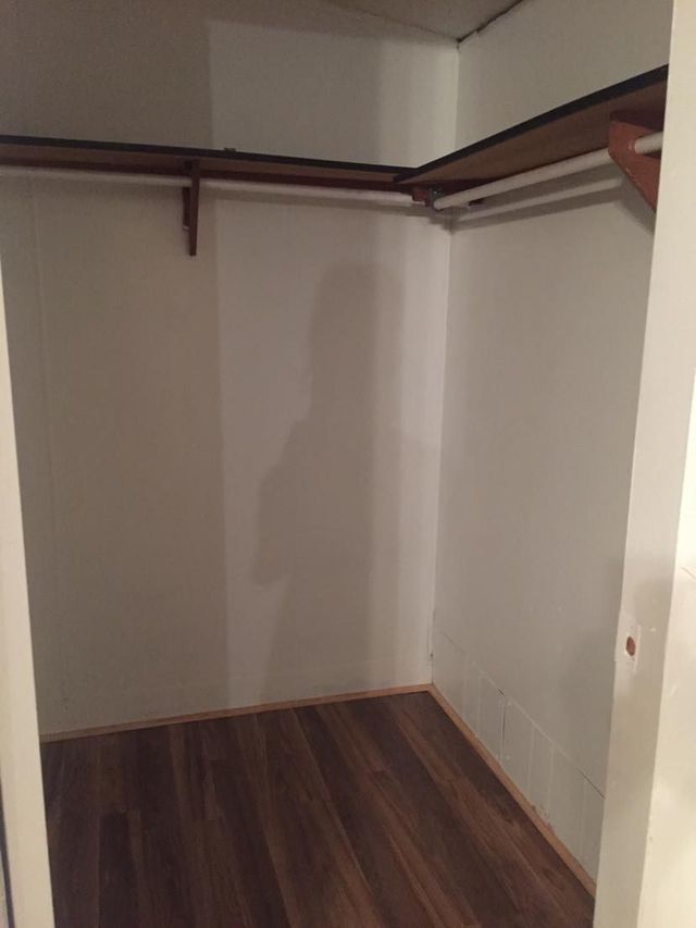 An empty walk in closet with wooden floors and shelves.