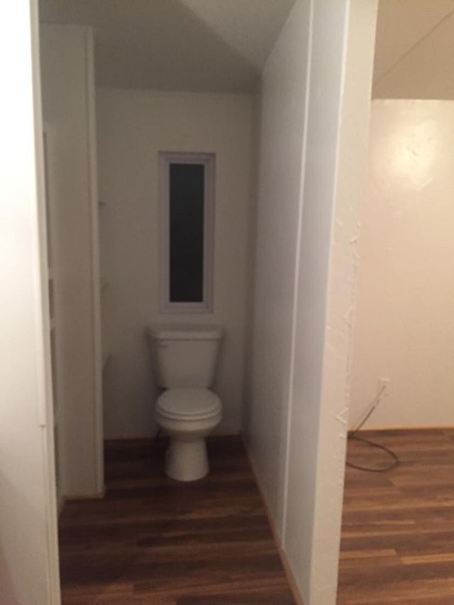 A bathroom with a toilet and a window.
