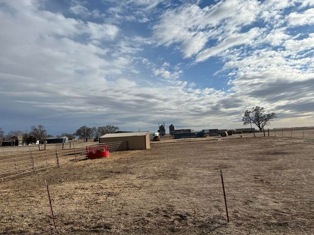A large dry grass field with a blue sky and clouds in the background.
