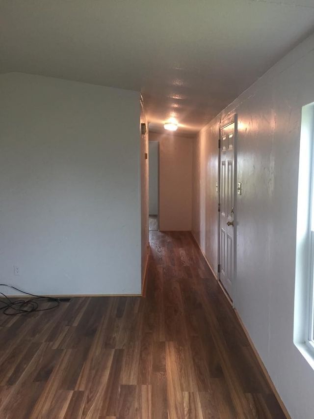 A long hallway in a house with hardwood floors and white walls.