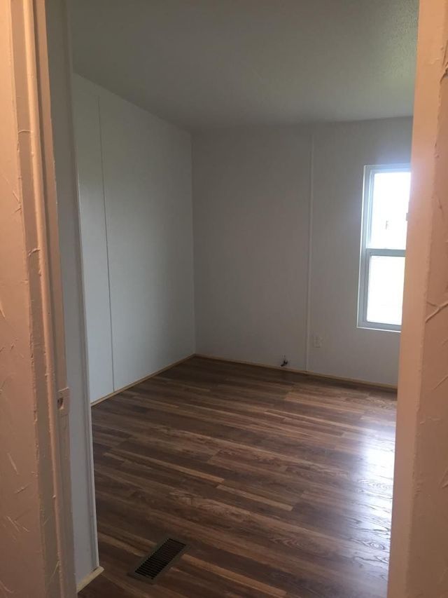 An empty room with hardwood floors and a window.