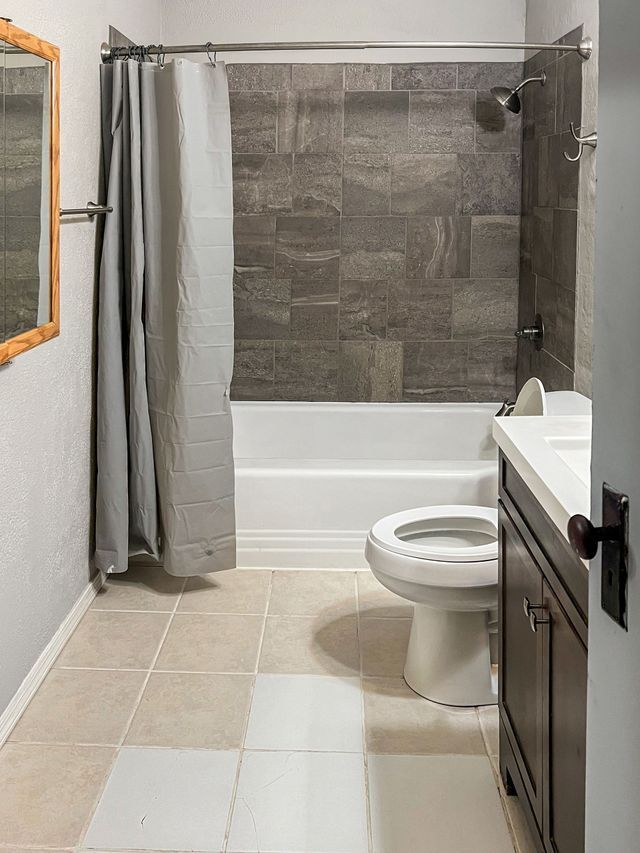 A bathroom with a toilet , sink , bathtub and mirror.