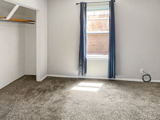 An empty bedroom with a window and a closet.