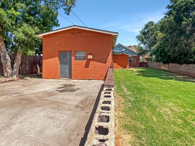 A red brick house with a fence and a grassy yard in front of it.
