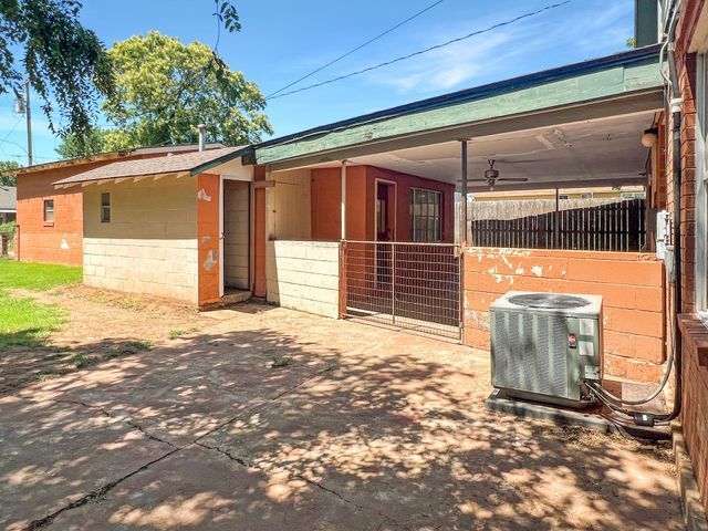 A house with a covered porch and an air conditioner in the backyard.