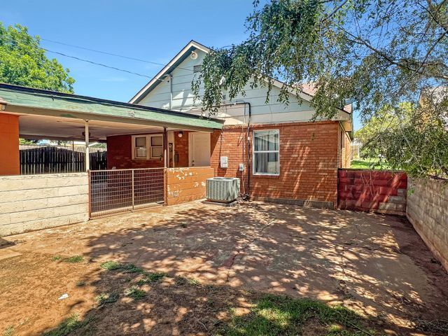 A brick house with a green roof and a fence in the backyard.