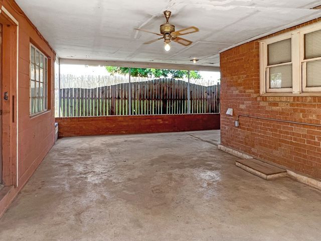 An empty room with a ceiling fan and a brick wall.