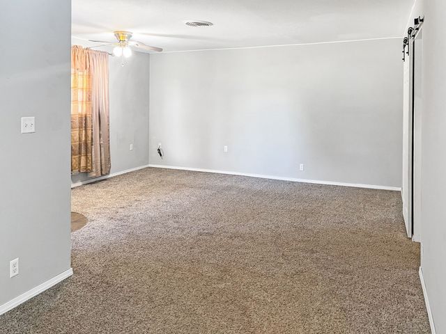 An empty living room with a brown carpet and white walls.