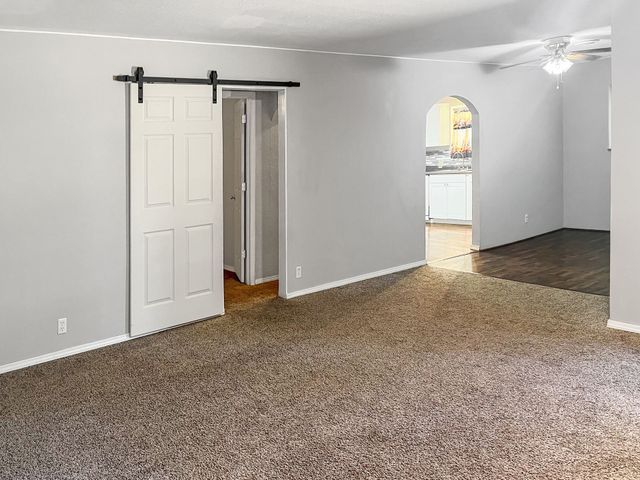 An empty living room with a sliding barn door and a ceiling fan.