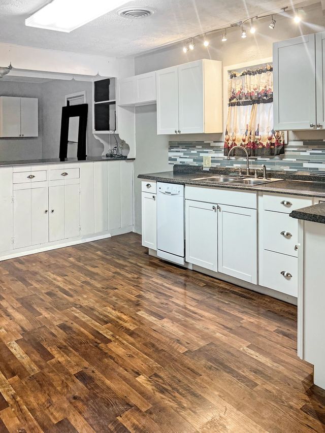 A kitchen with wooden floors and white cabinets