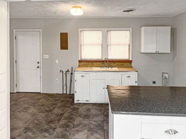 A kitchen with a sink , cabinets , and a granite counter top.