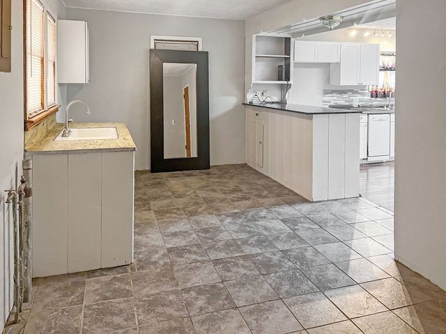 A kitchen with a sink , cabinets , and tile floor.