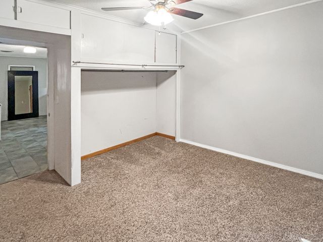 An empty bedroom with a ceiling fan and a closet.