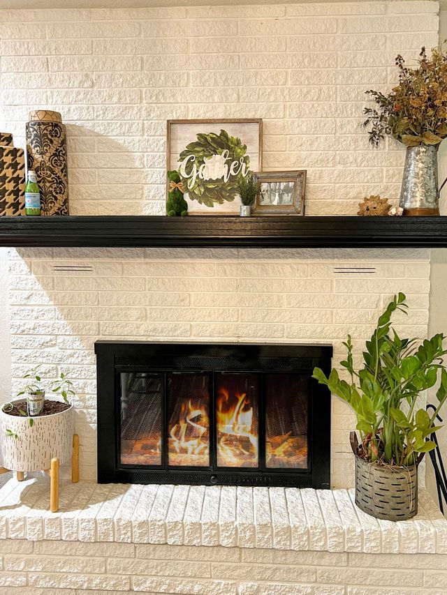 A white brick fireplace with a black door and a black mantle.