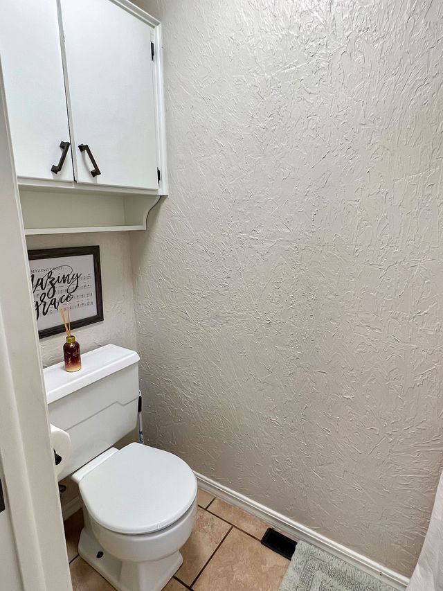 A bathroom with a toilet , cabinets and a picture on the wall.