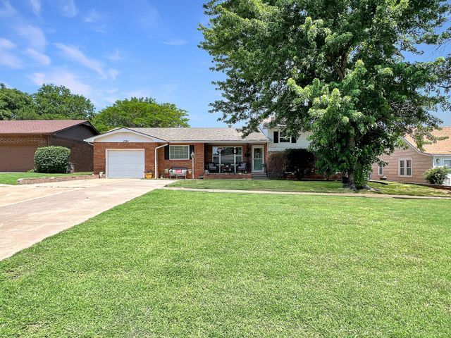 A house with a large lawn and a tree in front of it.